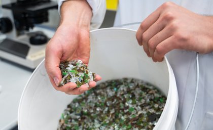 A bucket of mixed colour broken glass which can be used in the process.